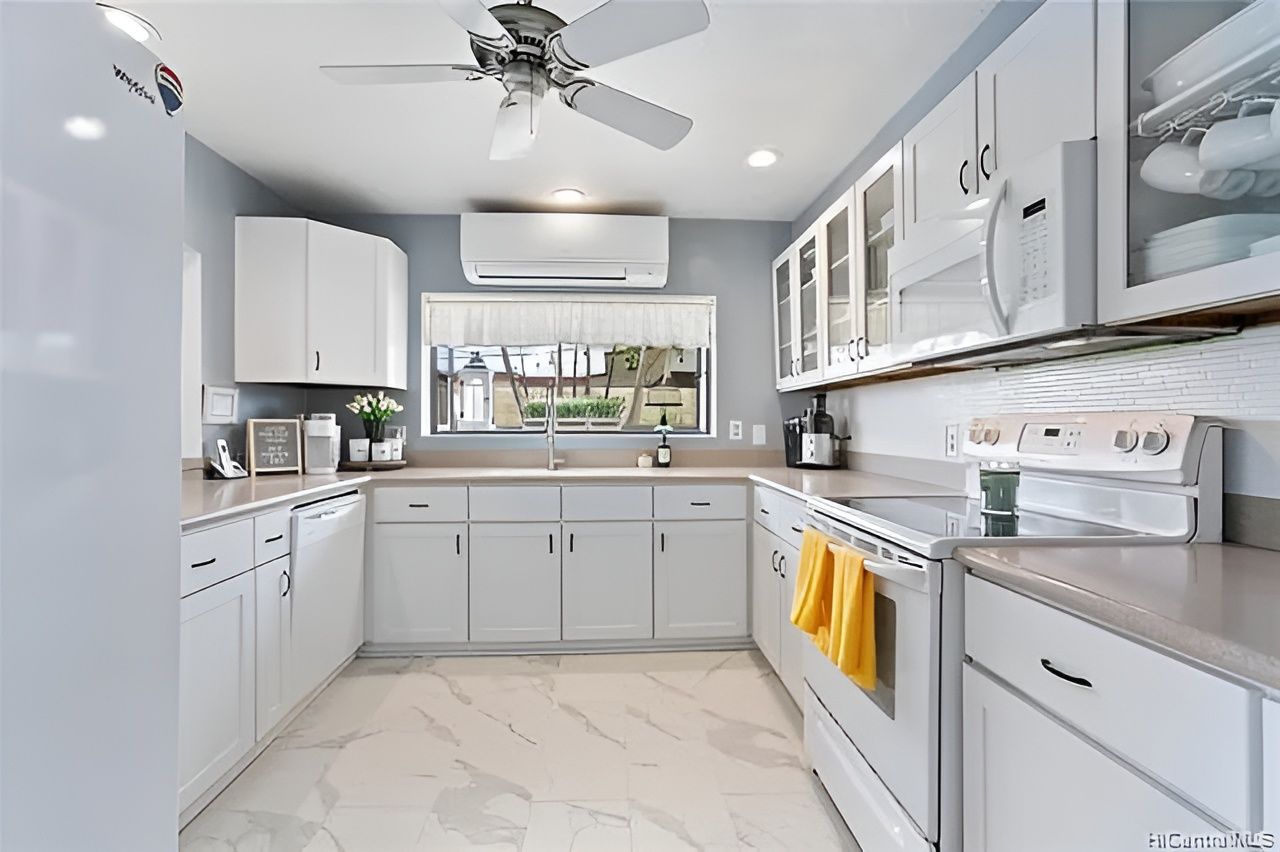 Bright and modern kitchen with white cabinets and stainless steel appliances.