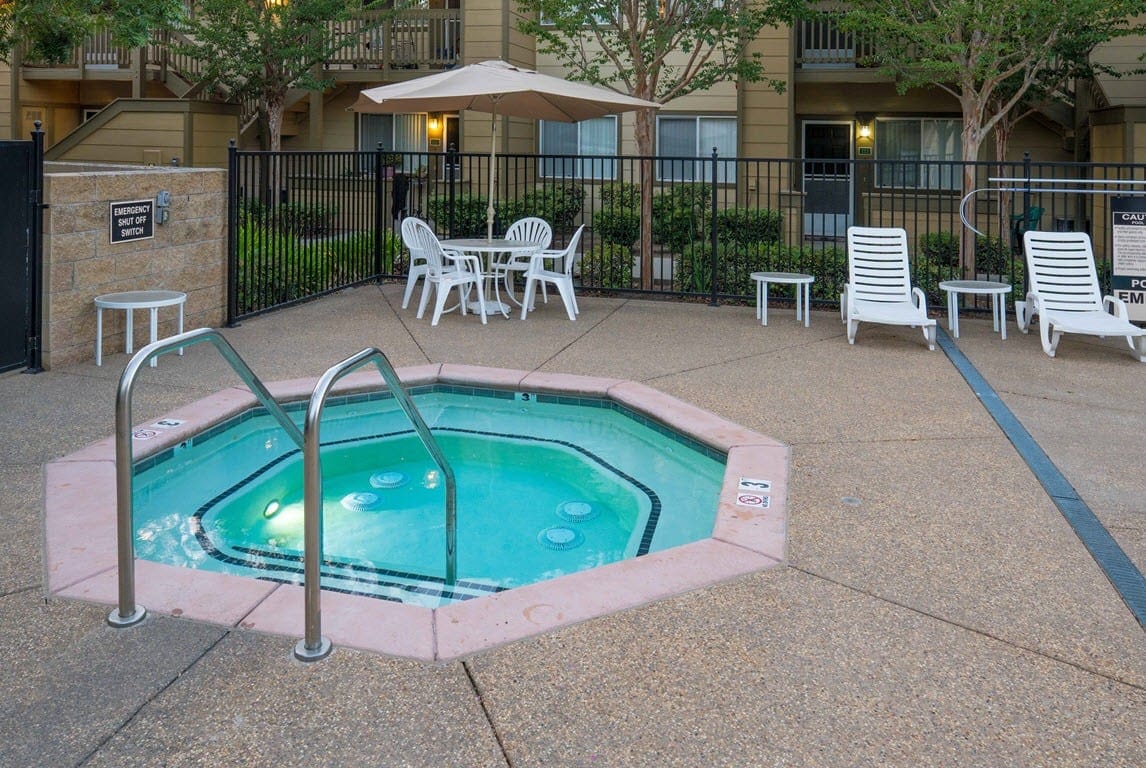 Hot tub area with chairs and umbrella at Vintage Glen Senior Apartments