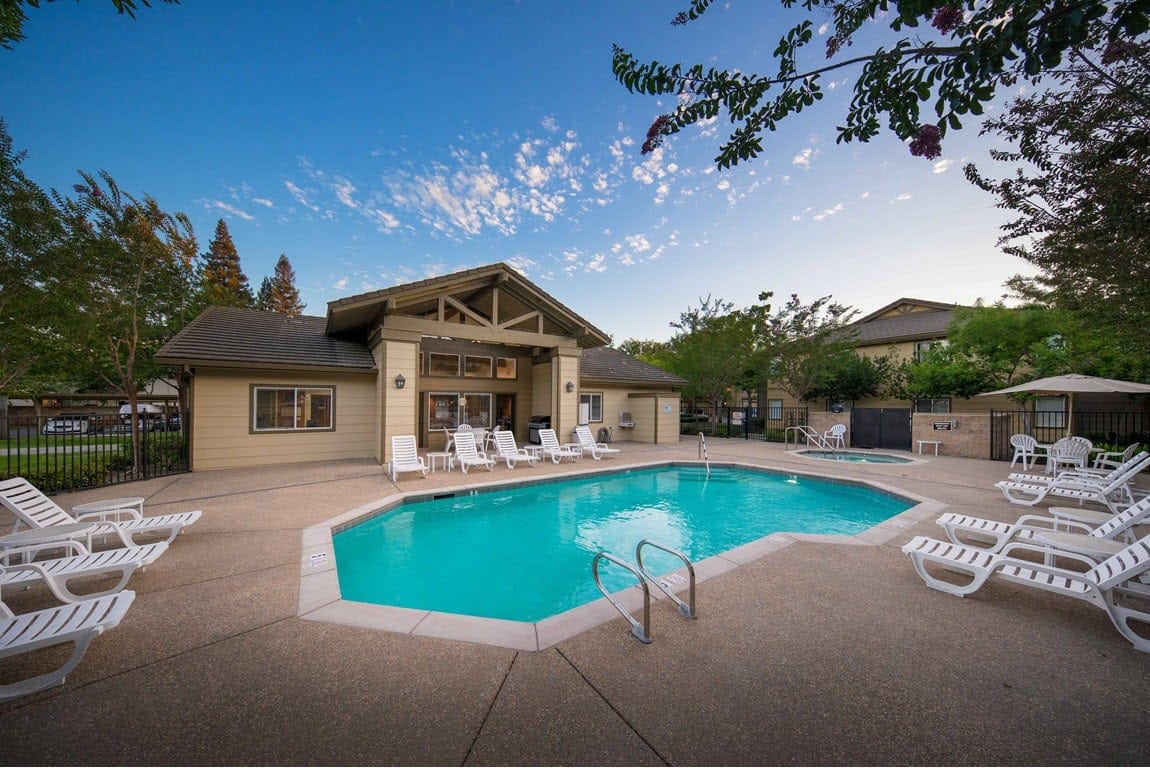 Outdoor swimming pool surrounded by lounge chairs and the facility building.