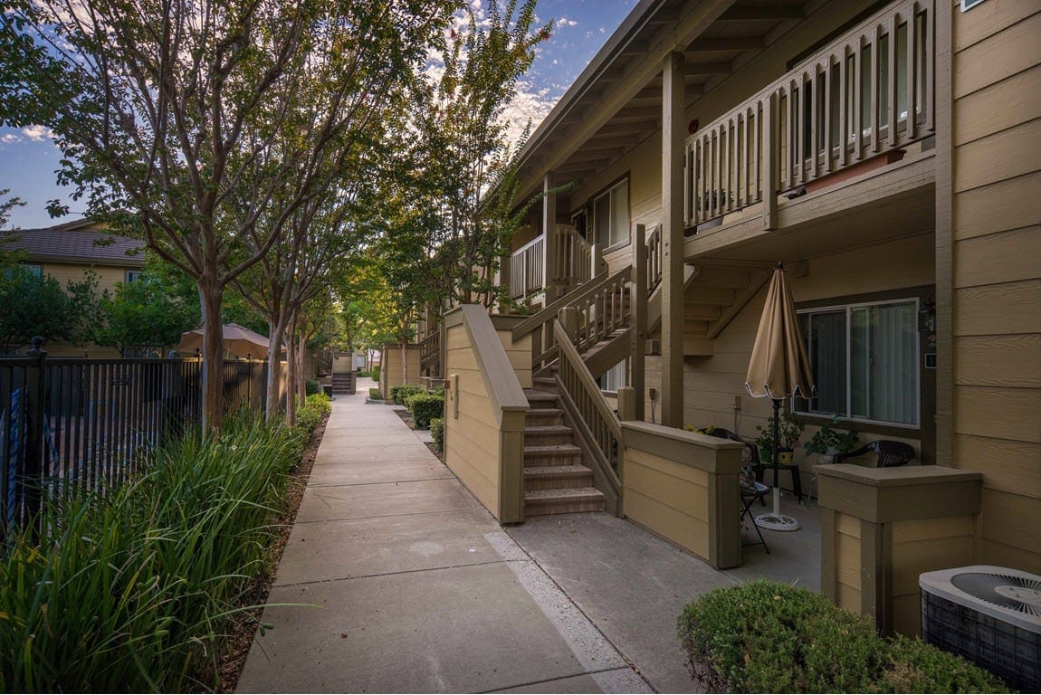 Walkway with greenery and apartment entrances at Vintage Glen Senior Apartments
