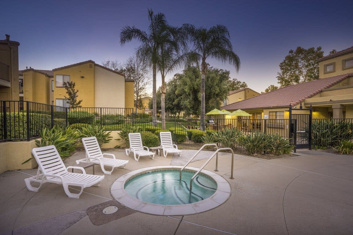 Outdoor hot tub surrounded by lounge chairs and greenery