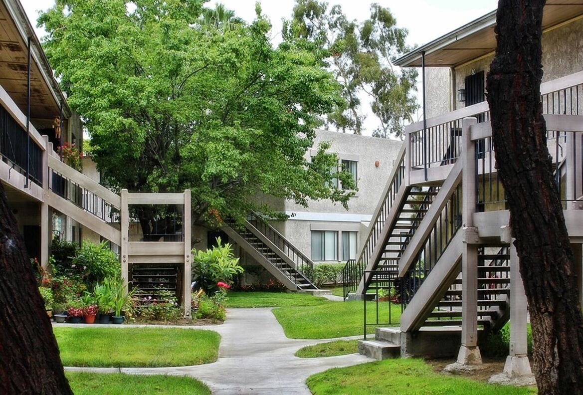 Courtyard view of Heritage Park Apartments with greenery and staircases.
