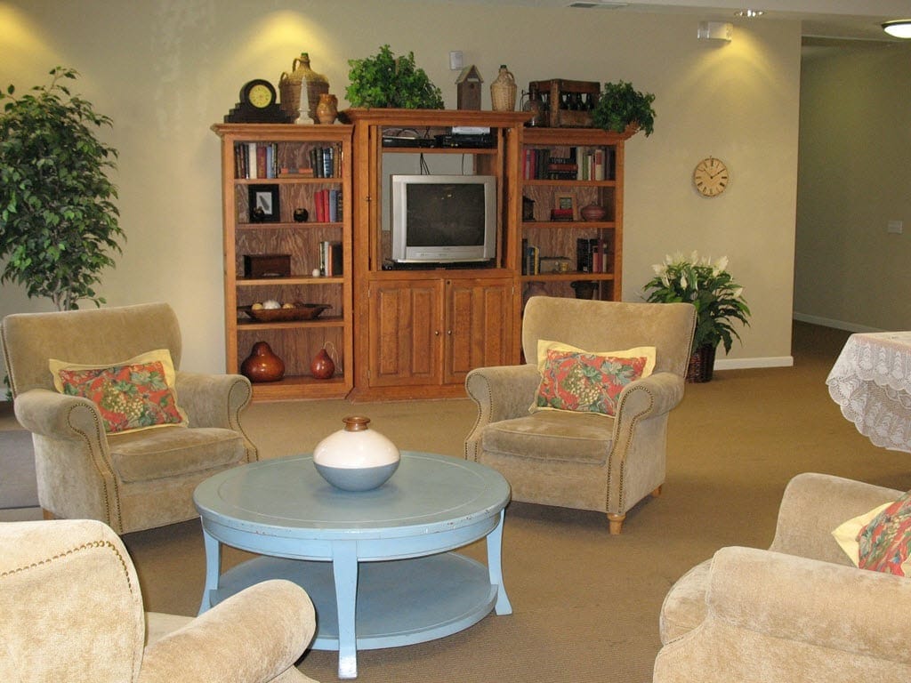 A cozy living room with armchairs, a coffee table, and a bookshelf.