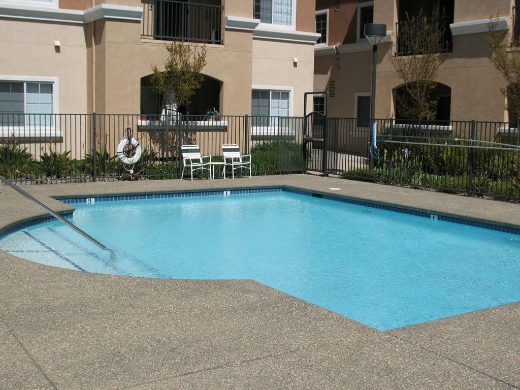 Outdoor swimming pool surrounded by a safety fence and lounge chairs