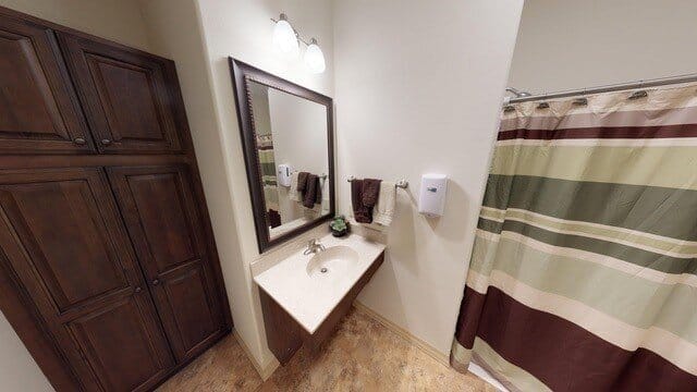Bright bathroom featuring a sink, mirror, and shower curtain.