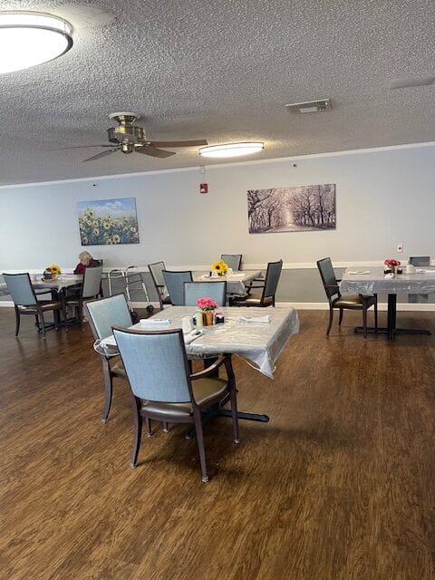 A spacious dining room with tables set for meals and artwork on the walls.
