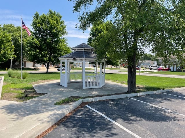 White gazebo surrounded by trees and green grass