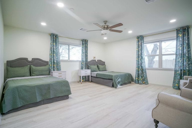 Spacious bedroom with two beds, a seating area, and natural light.