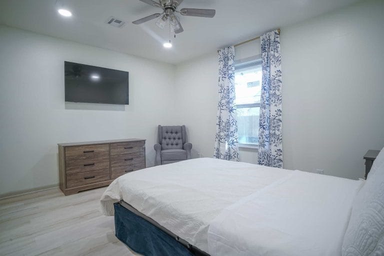 Comfortable bedroom with a TV, dresser, and chair