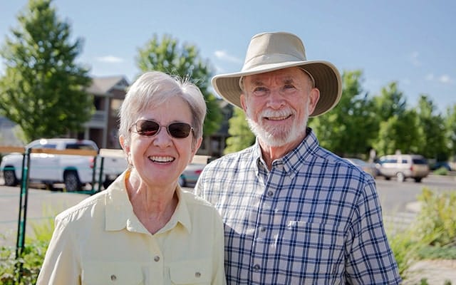 A senior couple smiling outdoors at the facility