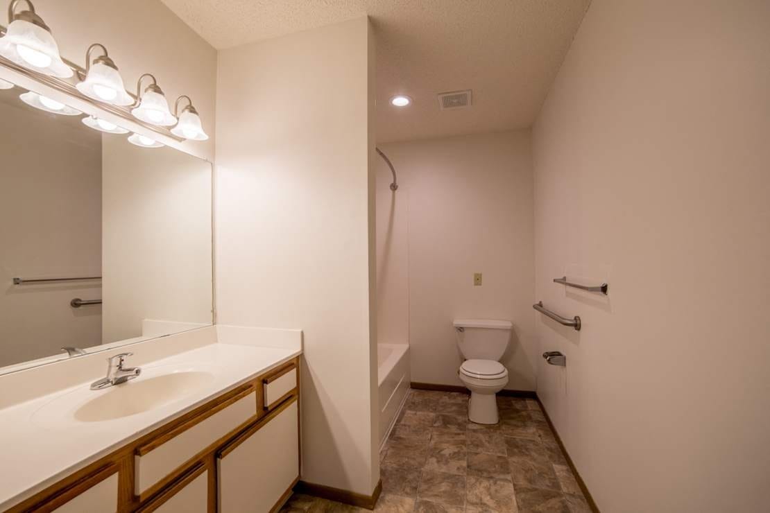 Brightly lit bathroom with a sink, toilet, and bathtub