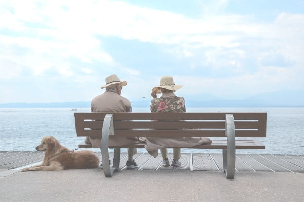 Two seniors enjoying a lakeside view on a bench.