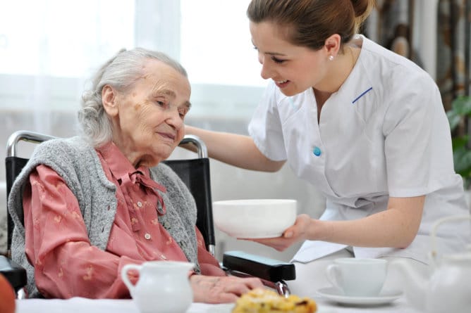 Caregiver serving food to an elderly resident.