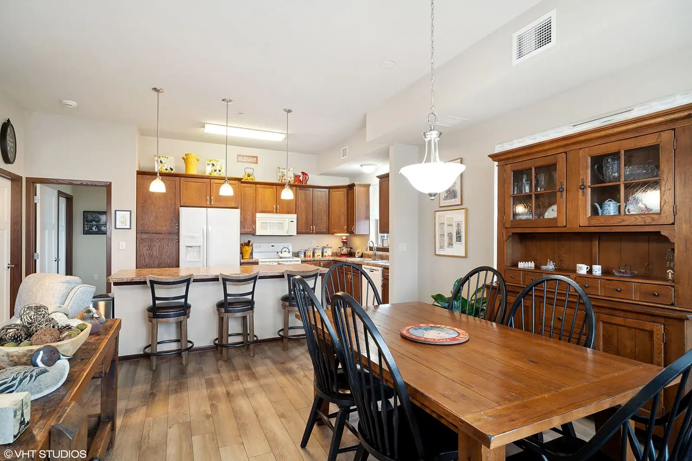 Dining area with a wooden table and kitchen appliances in the background