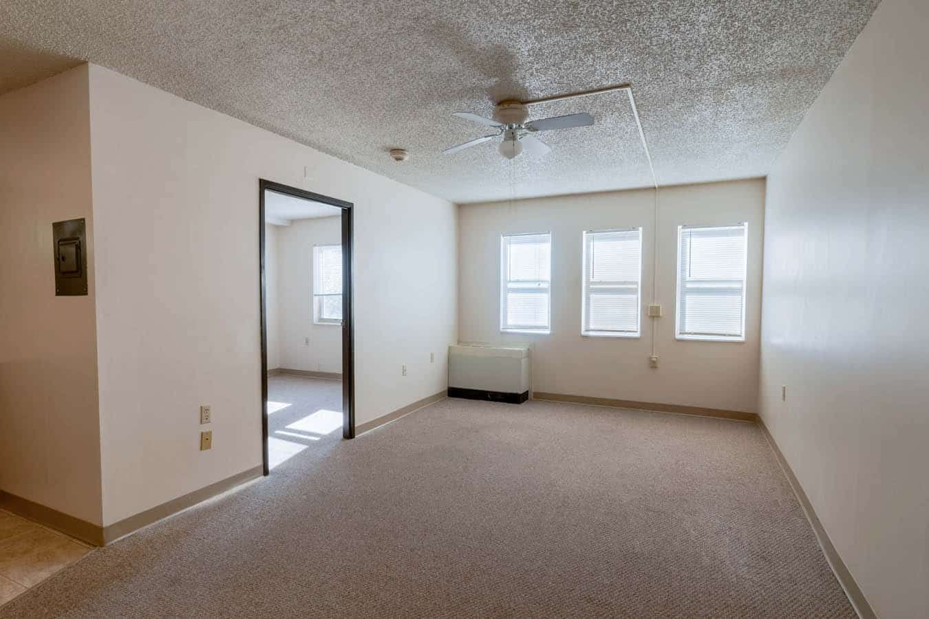 A bright living room with windows and a ceiling fan