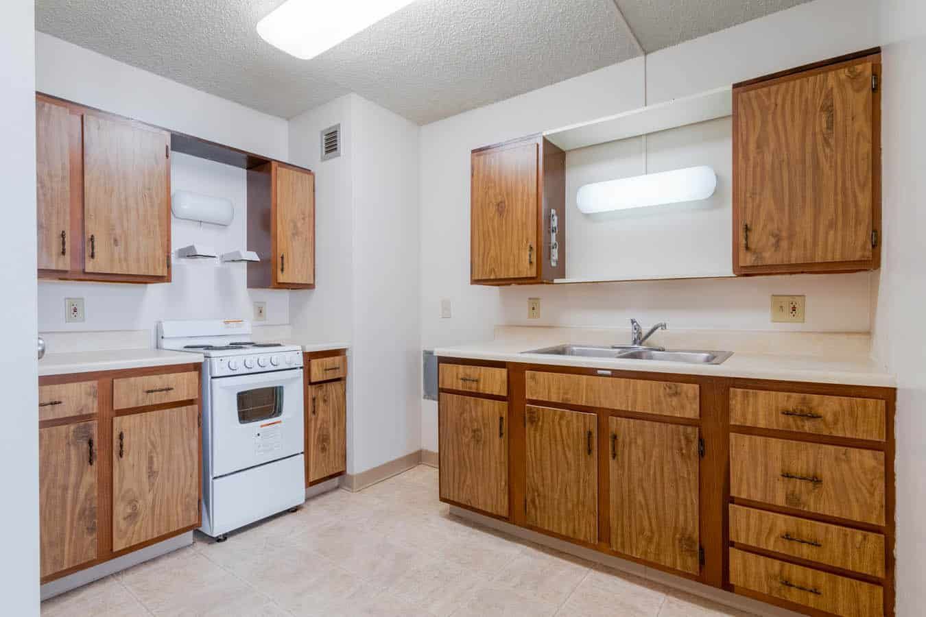 A spacious kitchen with wooden cabinets and a white stove.