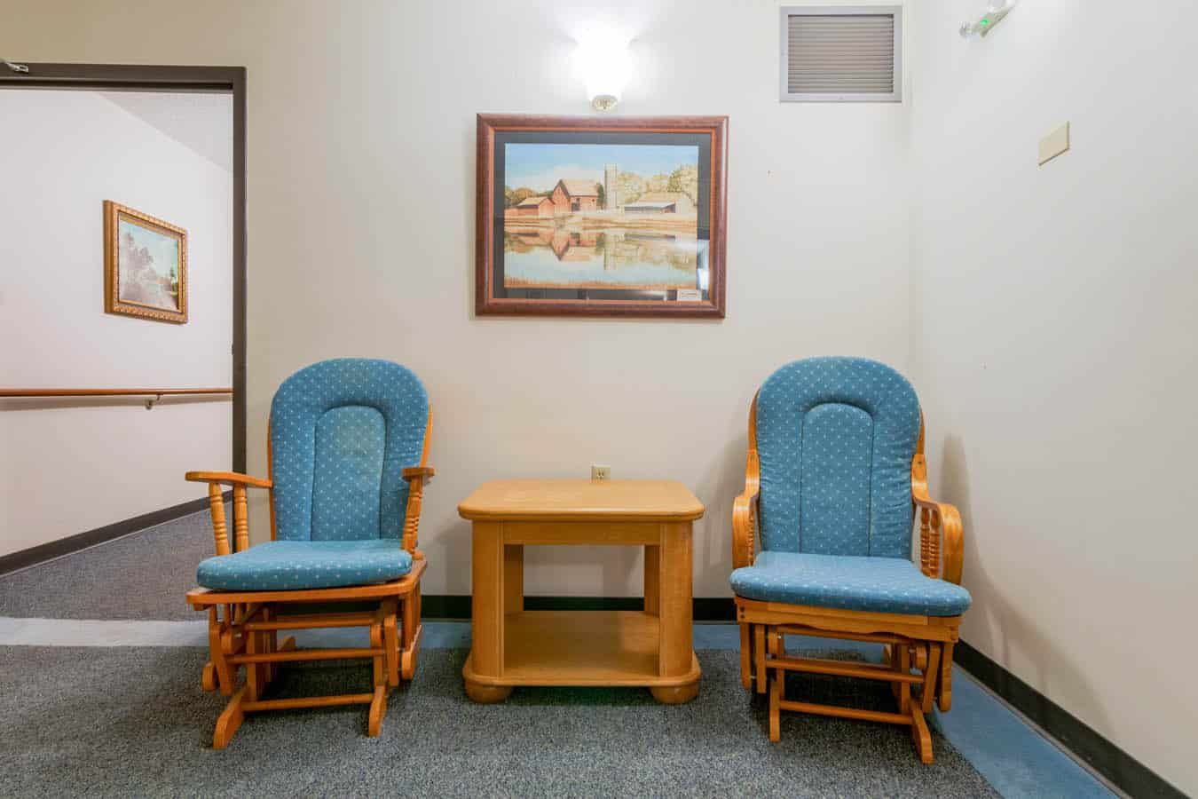 Two blue rocking chairs and a wooden table in a lounge area