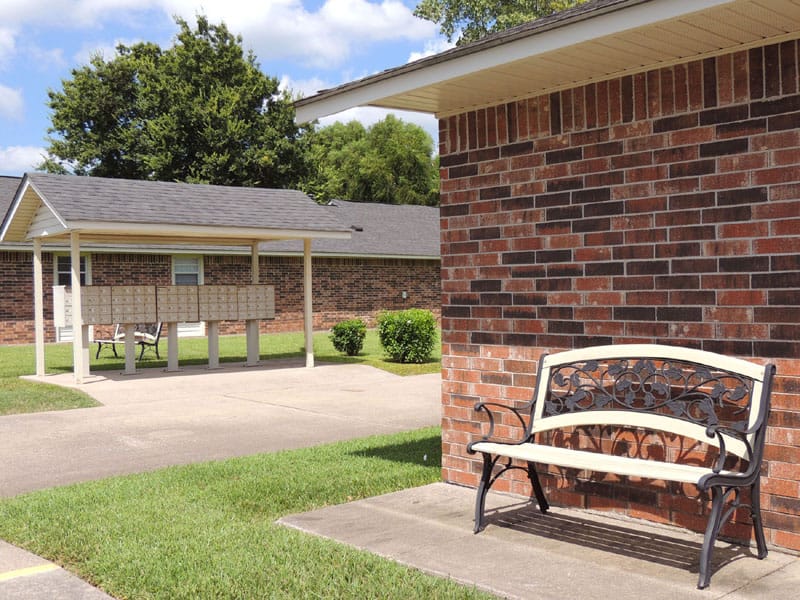A bench in front of a brick wall and mailboxes at Heritage Village.