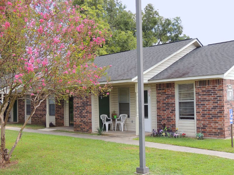 Exterior view of front entrance surrounded by floral landscaping