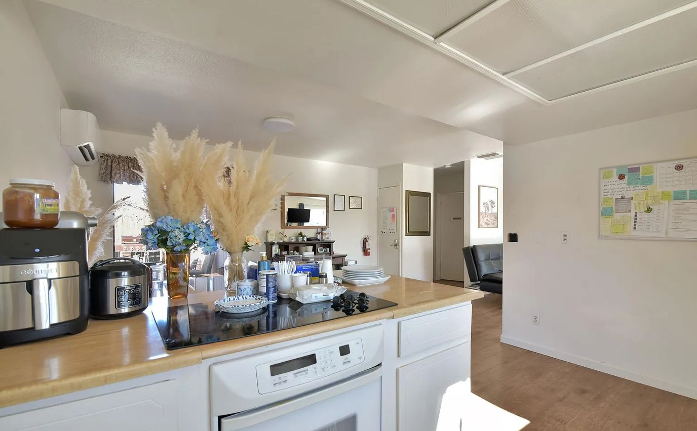 Bright kitchen countertop with appliances and decorative flowers.