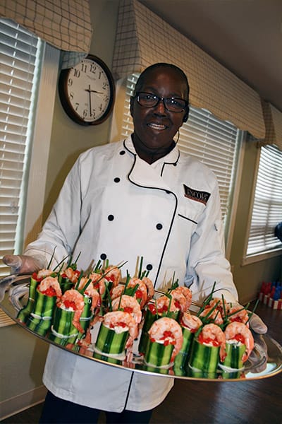 Chef presenting a tray of shrimp appetizers in the kitchen