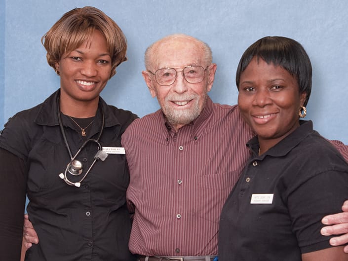 A resident smiling with two staff members
