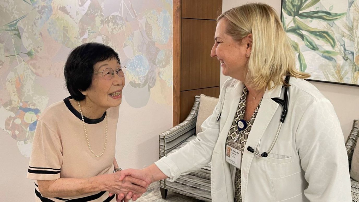 A resident and staff member smiling and shaking hands