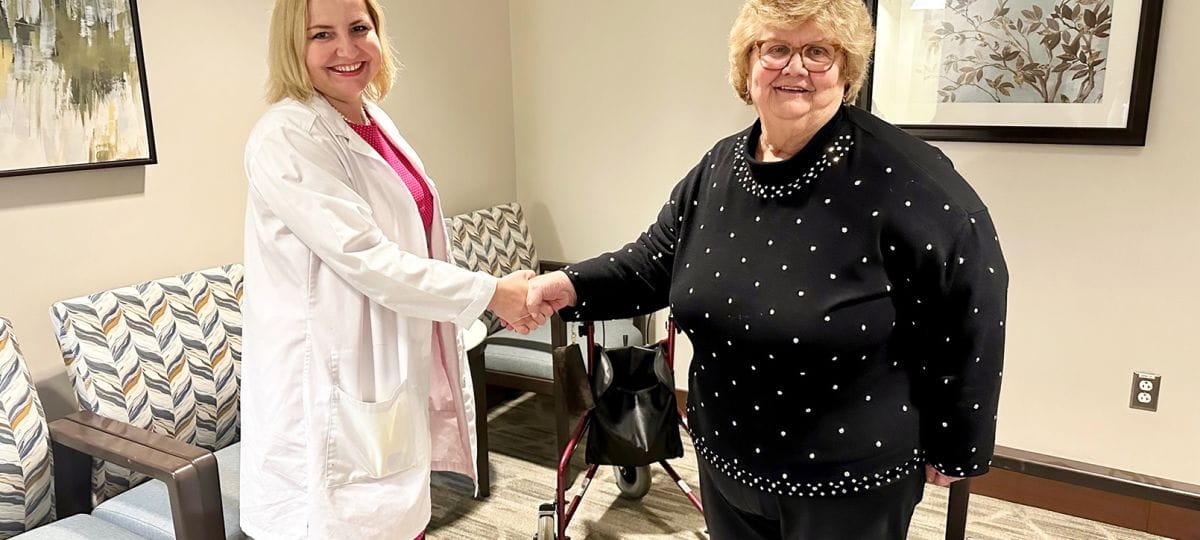 A healthcare professional shaking hands with a resident in a bright interior