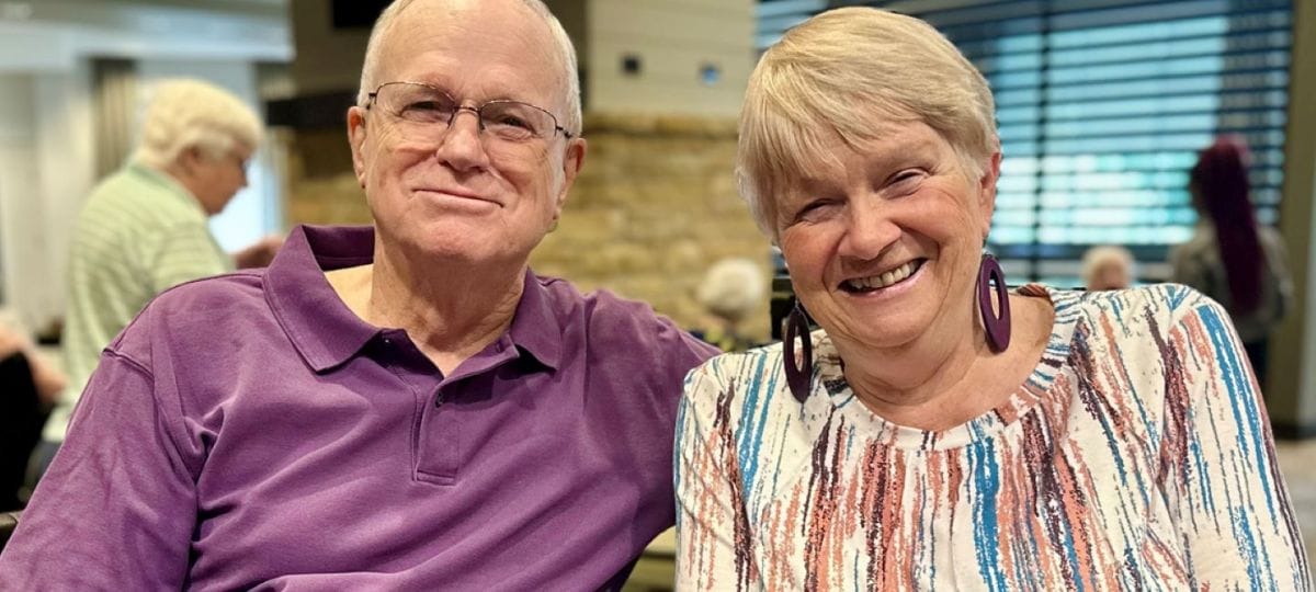 A smiling couple sitting together in a common area