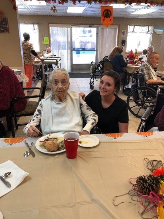 Resident enjoying a meal with staff support in a dining area