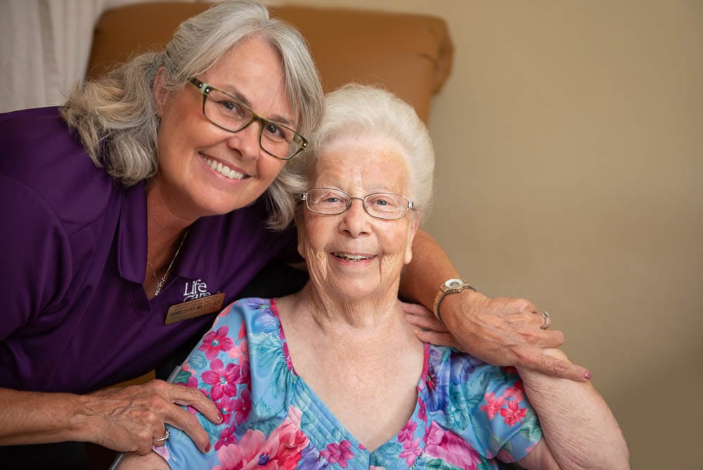 A staff member with a smiling resident in a care environment