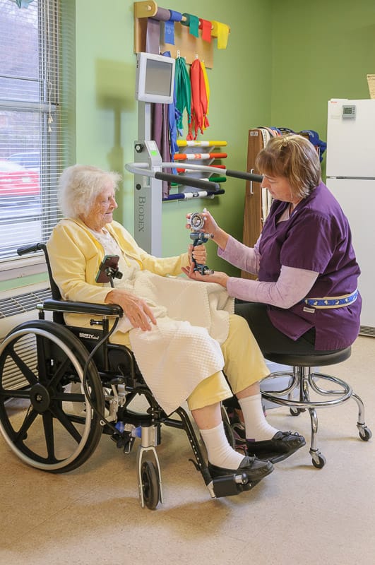 Staff assisting a resident in a warm interior setting