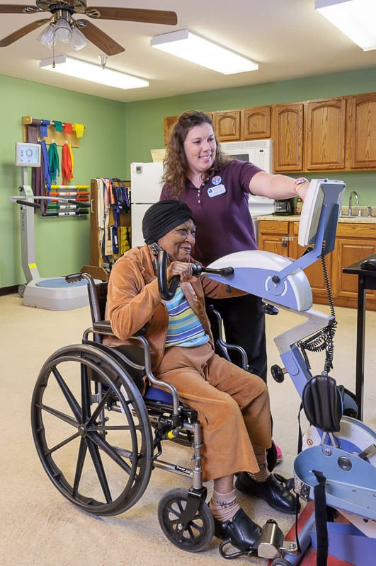 Staff assisting a resident in a therapy room