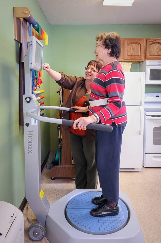 Staff assisting a resident with therapy equipment in an interior space