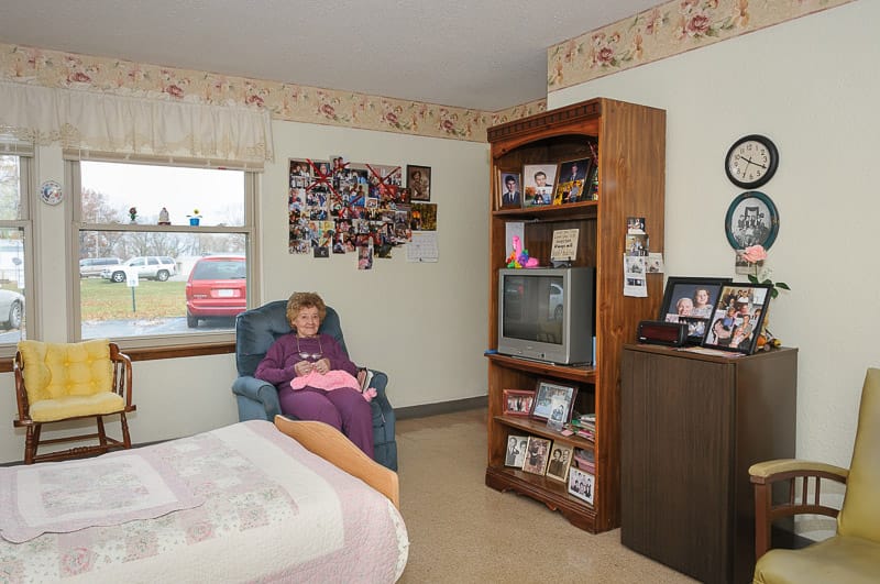 A resident relaxing in her room with personal items.