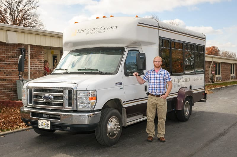 A staff member standing next to a facility vehicle