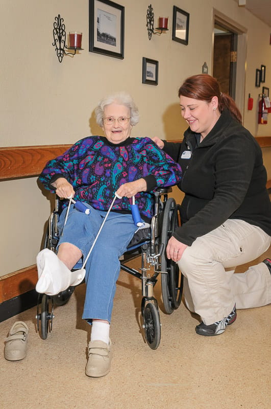 A caregiver assisting a resident in a hallway