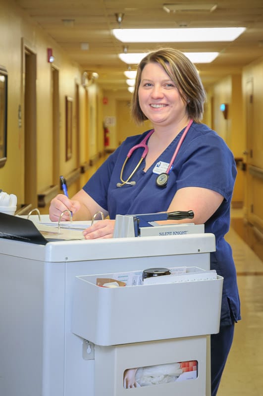 Nurse smiling while working at a care station
