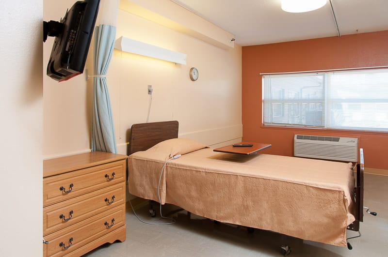 A private resident room with a bed and dresser