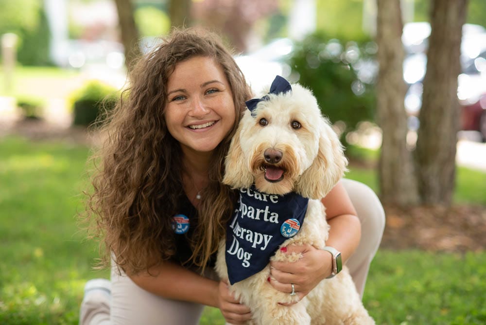 Staff member posing with a therapy dog outdoors