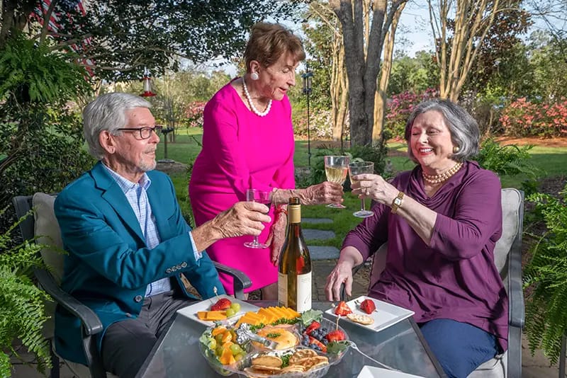 Residents toasting with drinks in a garden setting