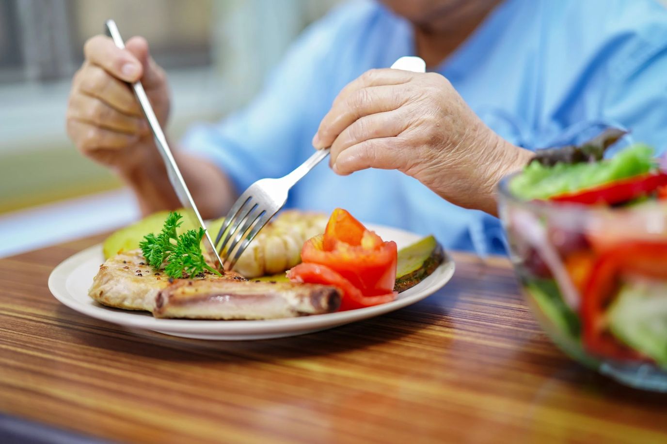 Resident enjoying a meal with vegetables on the table