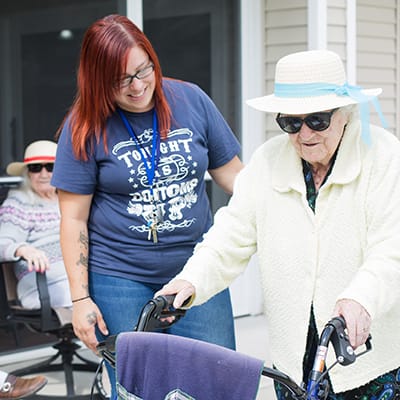 Resident using a walker with staff assistance outdoors