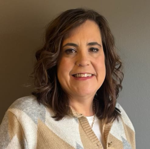 Portrait of a smiling woman against a plain wall.