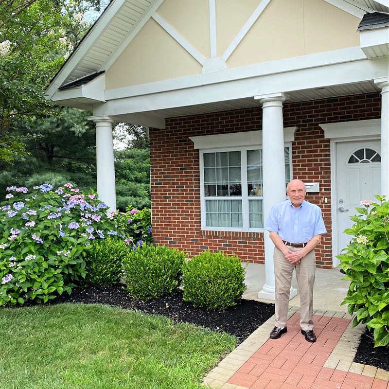Smiling resident standing in front of a facility entrance