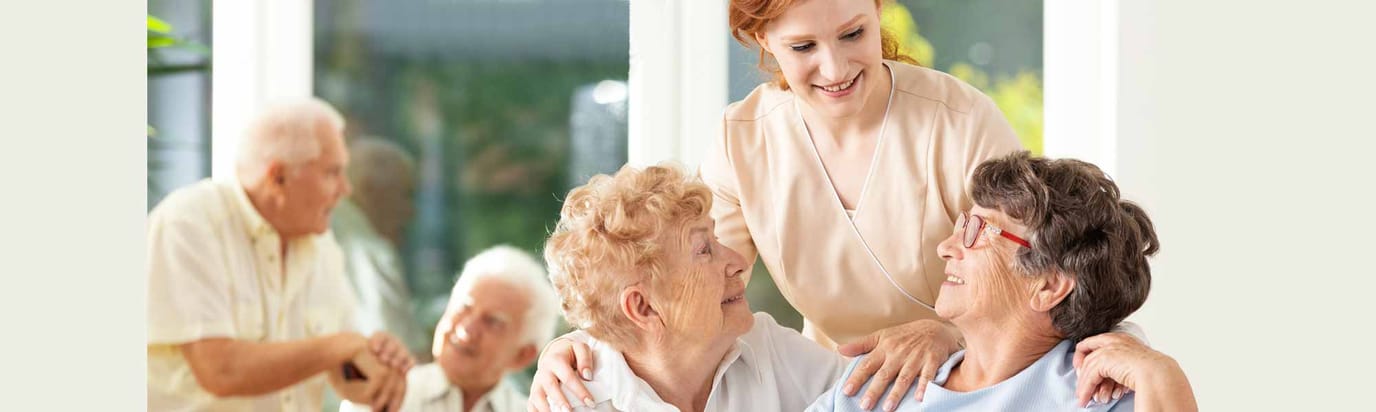 Residents smiling and interacting with a caregiver in a warm environment