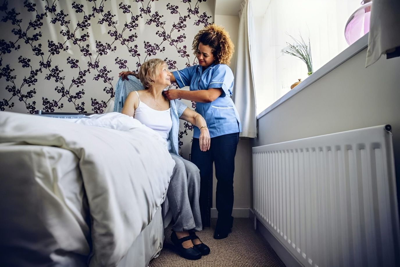 Staff assisting a resident in a cozy bedroom