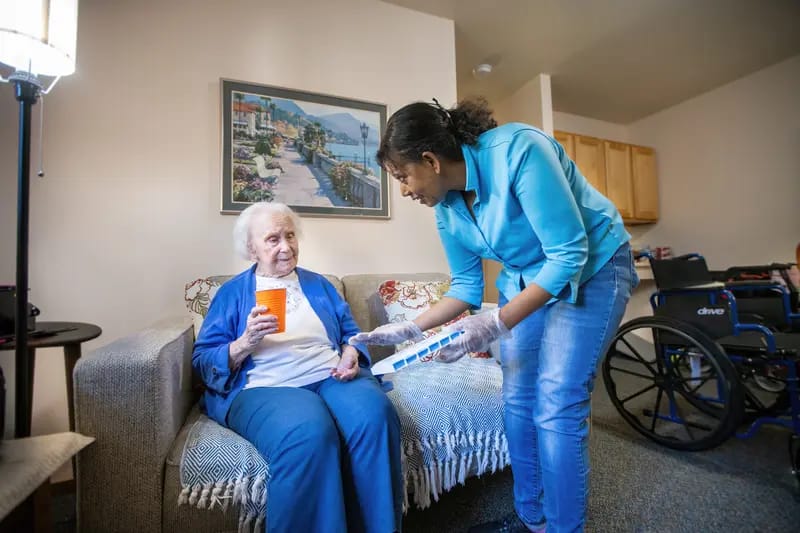 Care staff assisting a senior resident in an interior setting