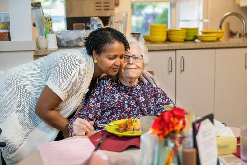 Staff member assisting a resident at a dining table