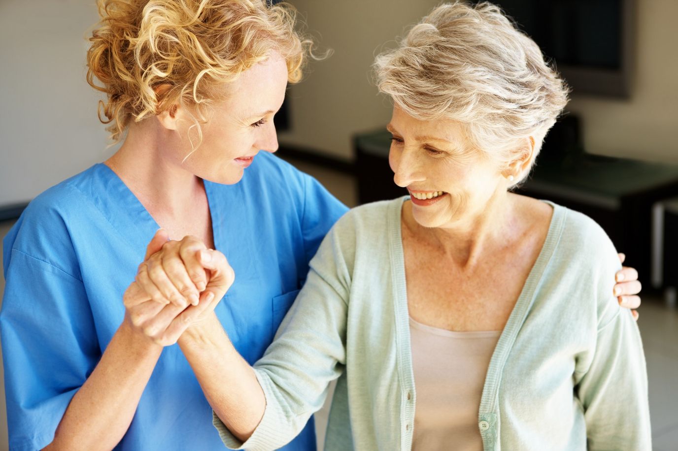 A staff member assisting a senior resident with a smile